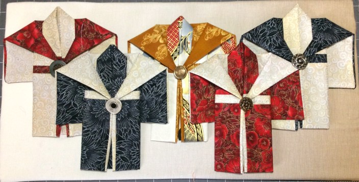Mounting on the shadowbox background with small pins at top and bottom of each kimono